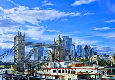 A bridge over water with a city in the background

Description automatically generated